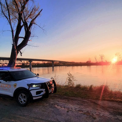 A patrol car at a lake at sunset