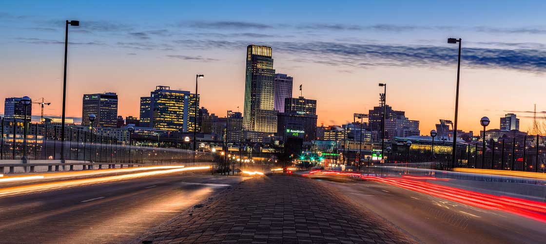 The beautiful skyline of Omaha sits as a backdrop to the bridge connecting Iowa and Nebraska as cars zoom by.